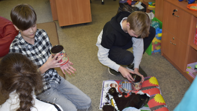 Bērni stādīja puķes, kuras pagaidām augs bibliotēkā, un bērni vēlāk varēs ieraudzīt, kas izauga no viņu iestādītajām sēklām.