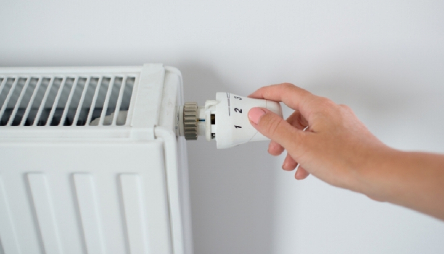 ilustratīvs foto ar roku pie termostata
